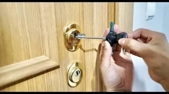 Close-up of an opening tool in the lock of a wooden door