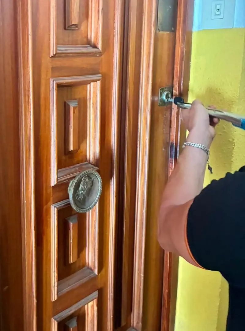 Professional intervenint en el pany d'una porta de fusta